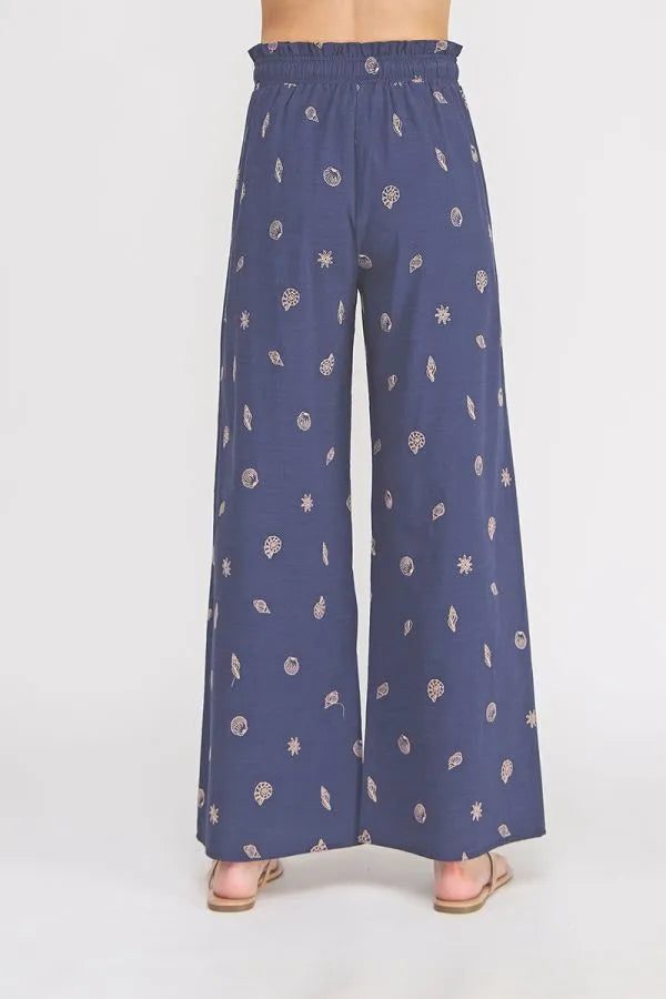 Navy blue wide-leg pants with seashell ruffle waist and elastic tie featuring white and light pink embroidered motifs