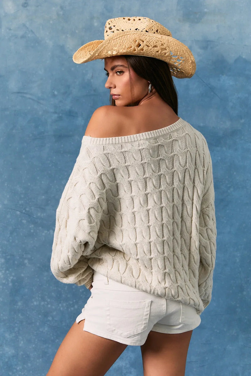 Off-the-shoulder cream-colored cable-knit sweater featuring a boat neck american flag design in soft knit material