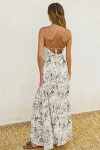 Off-white flowing maxi dress with black palm tree print and delicate crisscross straps shown from the back ocean vibes knot