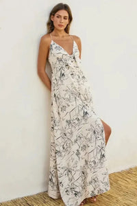 Off-white flowing maxi dress with black palm tree line art, thin straps, and v-neckline ocean vibes knot front design