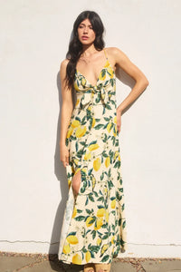 A flowing off-white maxi dress with a vintage lemonade knot front featuring yellow lemons and green leaves pattern