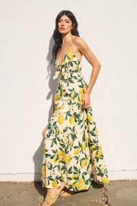 A flowing off-white maxi dress with a vintage lemonade knot front and vibrant yellow lemon and green leaf pattern