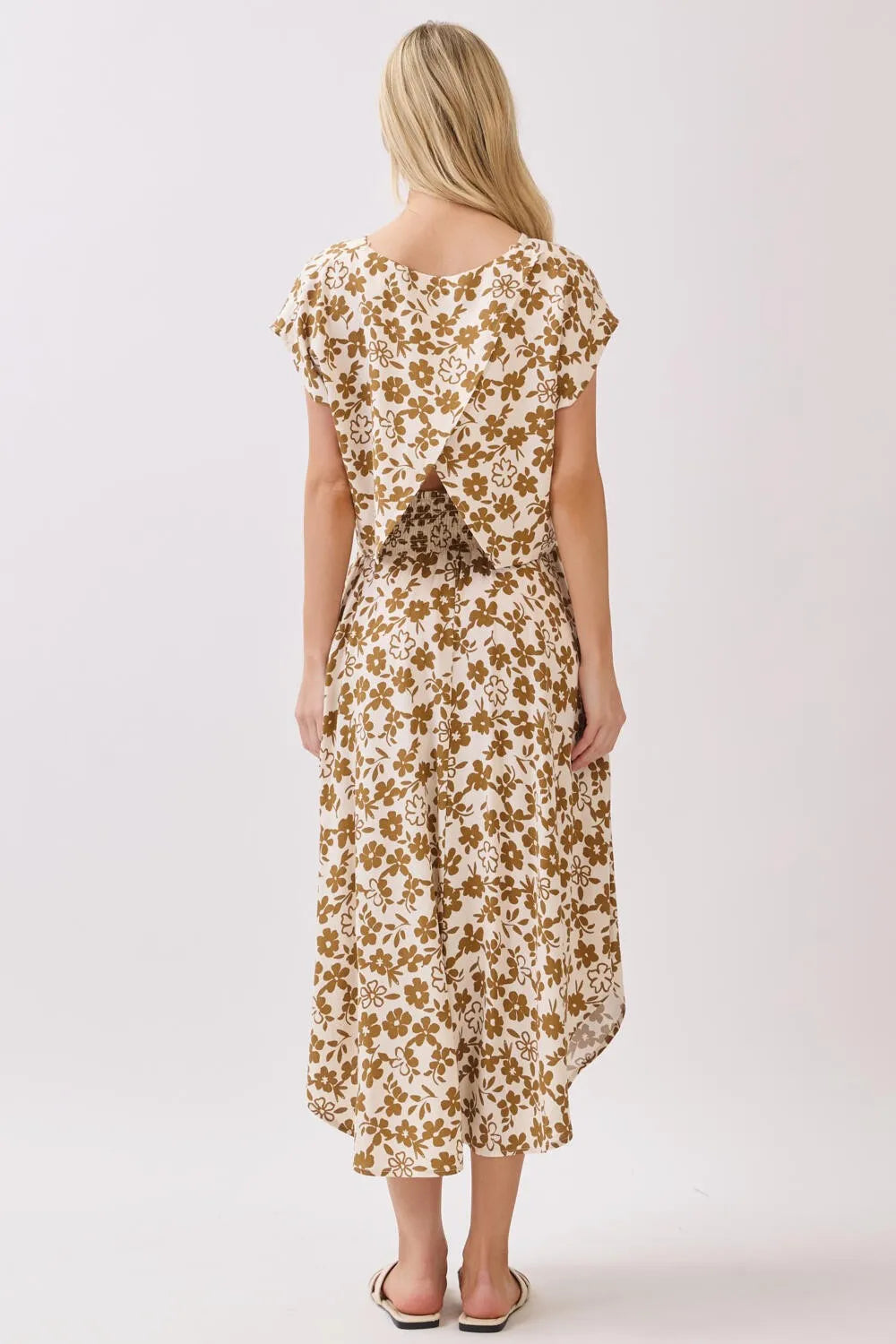A flowing off-white midi skirt with a delicate brown floral pattern featuring a smocked waistband and flutter sleeves