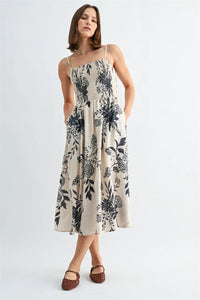 A flowing off-white midi dress with black botanical print and thin spaghetti straps smock design