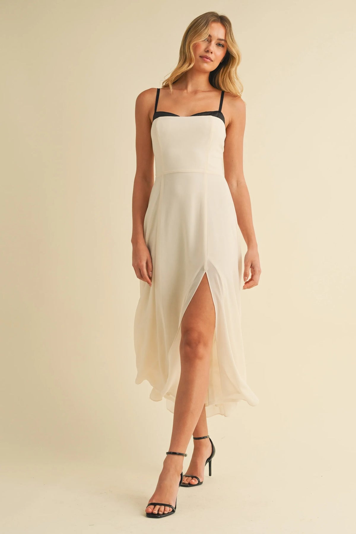 A flowing off-white midi dress with sweetheart neckline contrast straps and a high slit for elegant occasions