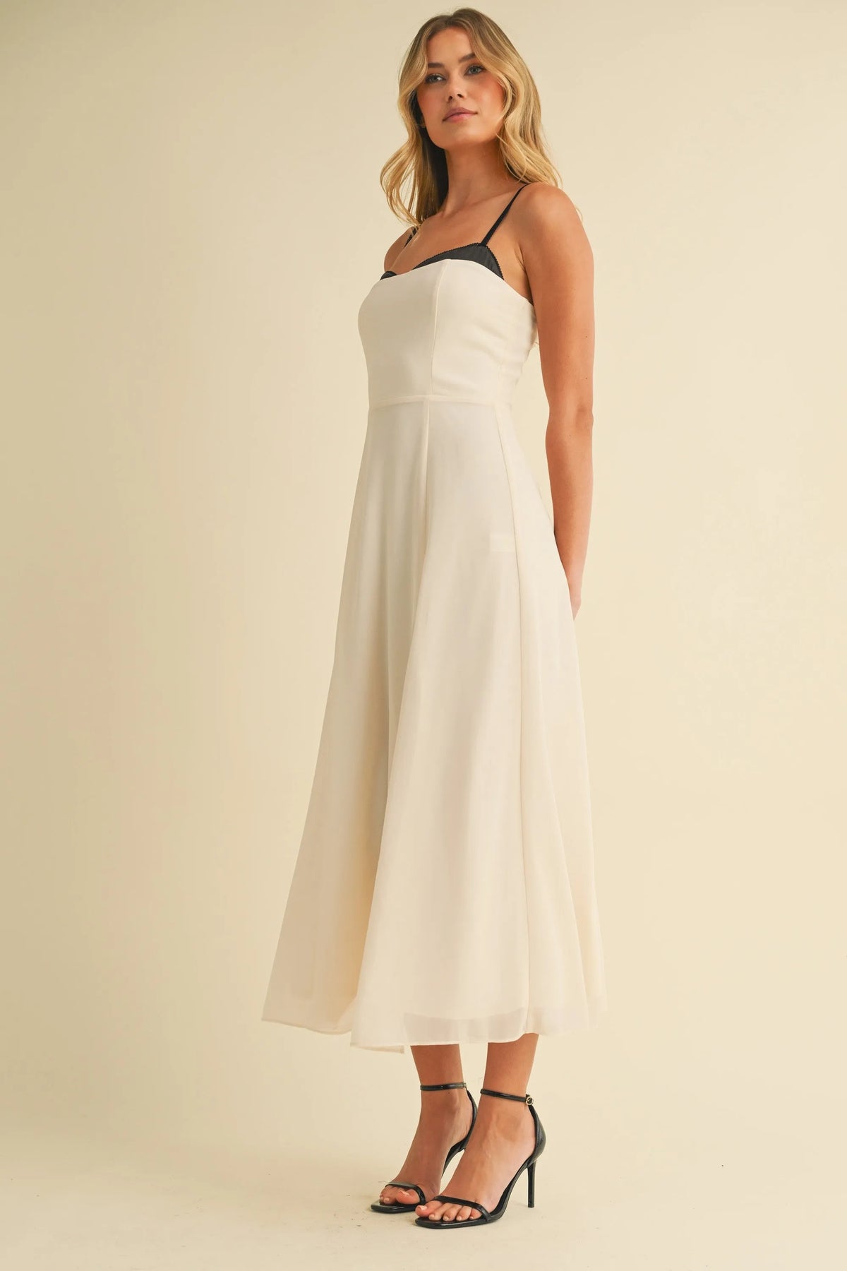 A flowing off-white midi dress with sweetheart neckline contrast straps and a subtle gathered waistline