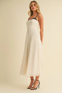 A flowing off-white midi dress with sweetheart neckline contrast straps and a subtle gathered waistline