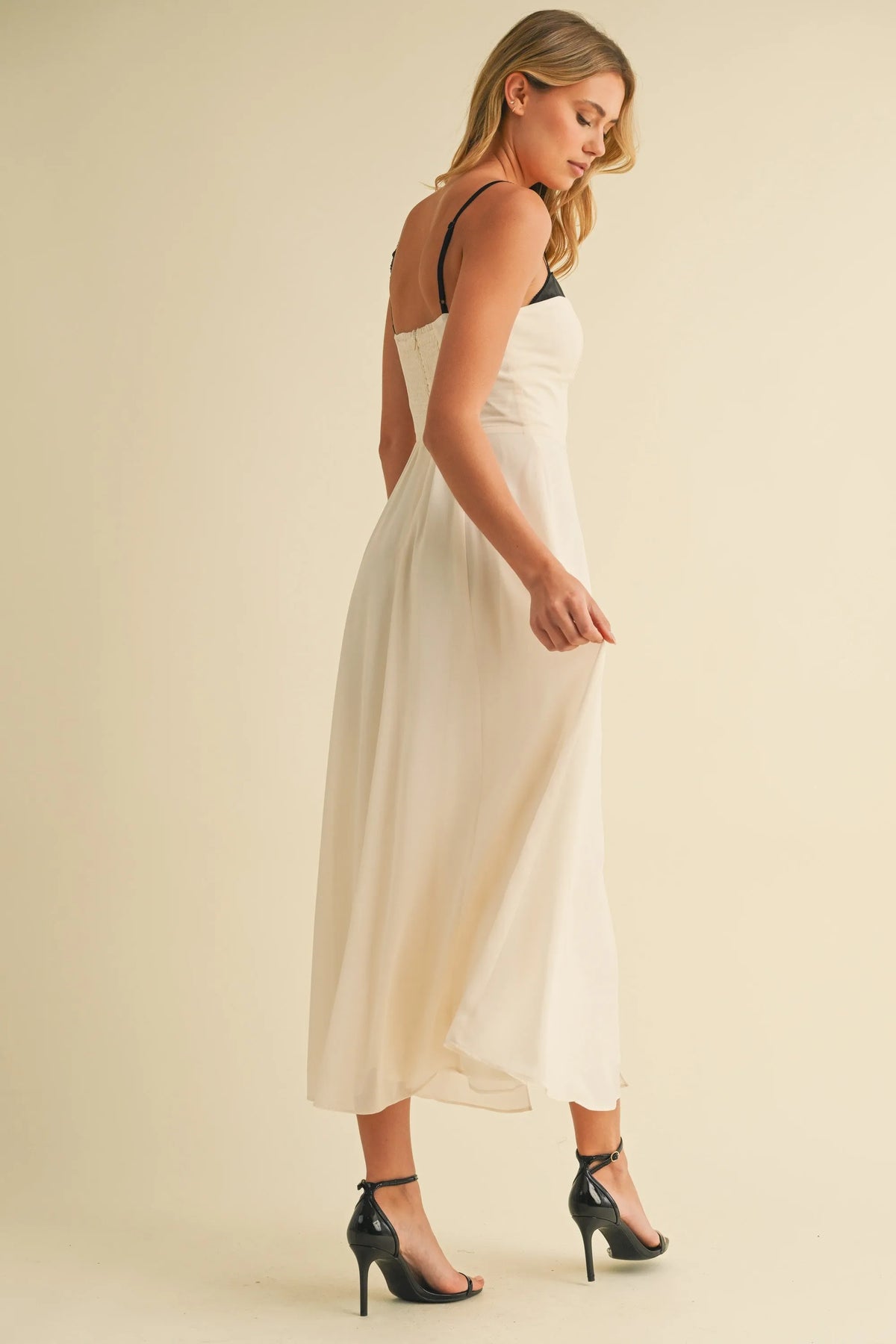 A flowing off-white satin midi dress with sweetheart neckline contrast straps in black spaghetti style