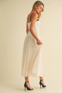 A flowing off-white satin midi dress with sweetheart neckline contrast straps in black spaghetti style