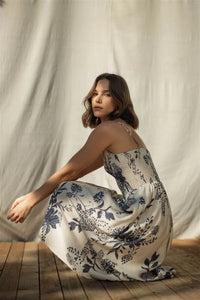 A flowing off-white midi dress with delicate navy blue floral embroidery and thin spaghetti straps smock detail
