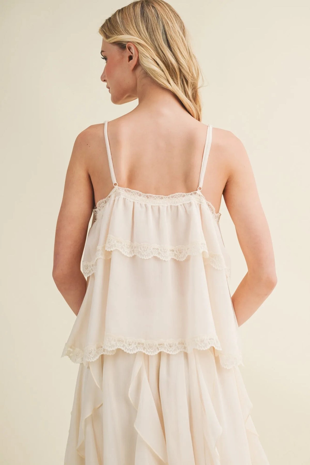 Off-white delicate lace inset tiered camisole with flowing fabric lace trim straps and ruffled hem