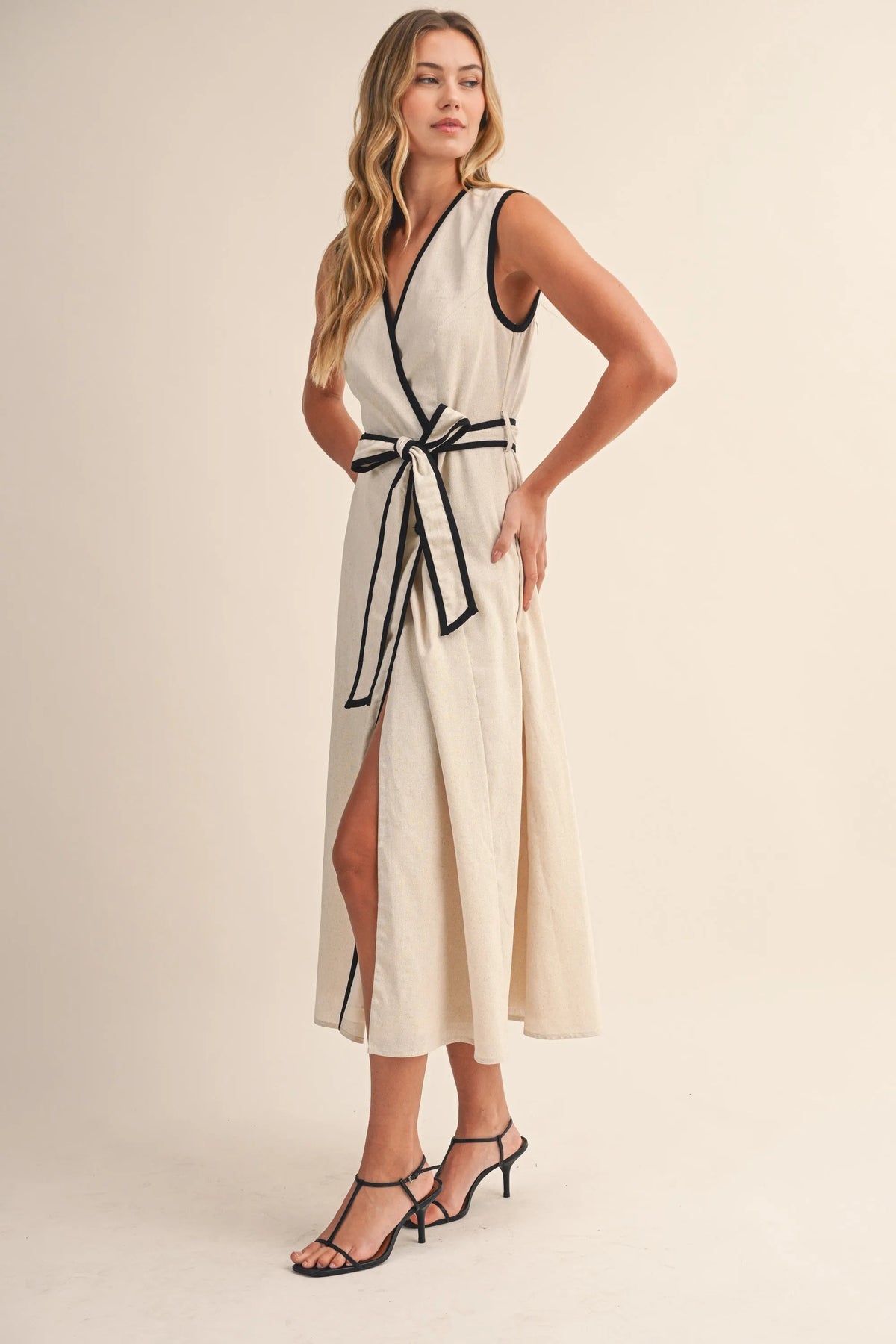 Off-white midi dress with black contrast piping wrap design along neckline waistband and side slit