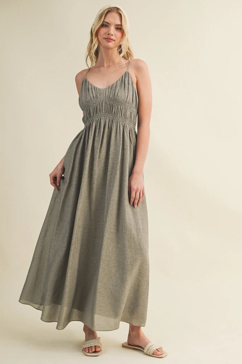 A flowing olive green maxi dress featuring a shirred bodice spaghetti strap and delicate straps for elegant wear