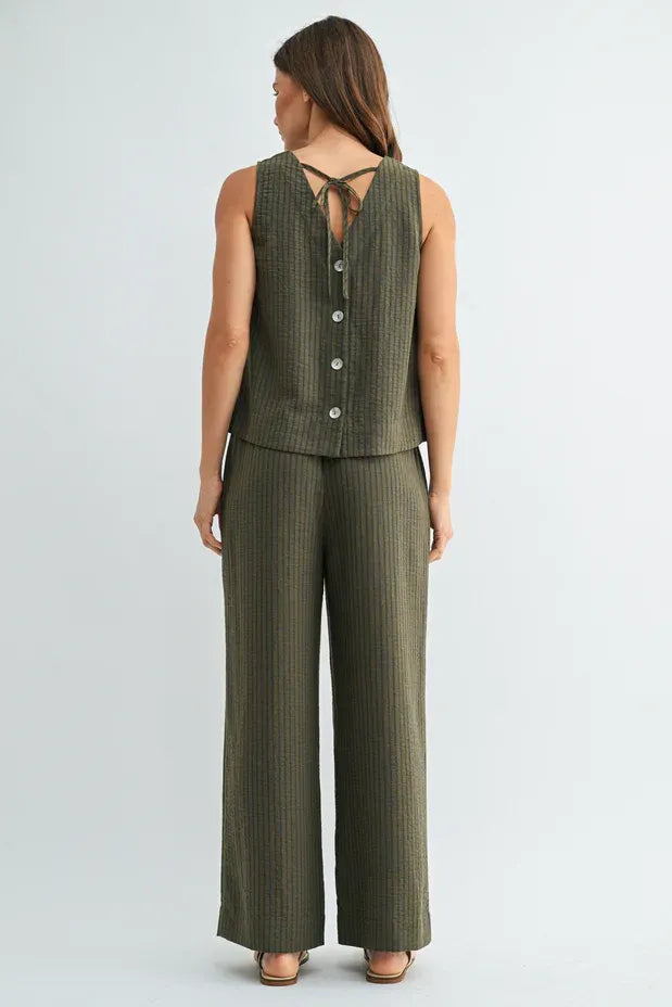 Olive green ribbed knit sleeveless top with button closure and back tie detail paired with elastic waist tie pants