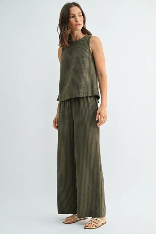 Olive green ribbed knit sleeveless top with relaxed fit and tiered hemline paired with elastic waist tie pants