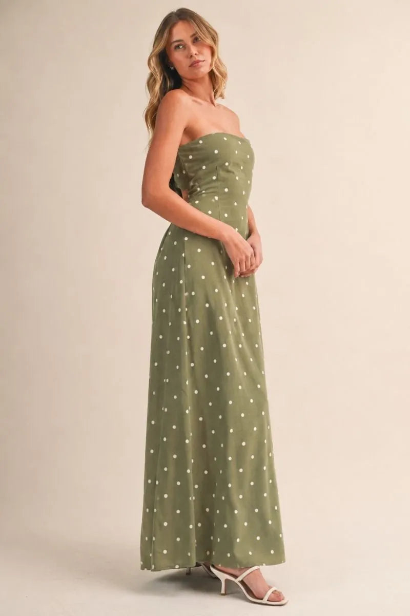 A flowing olive green polka dot tube strapless maxi dress with small white dots and a tie back detail