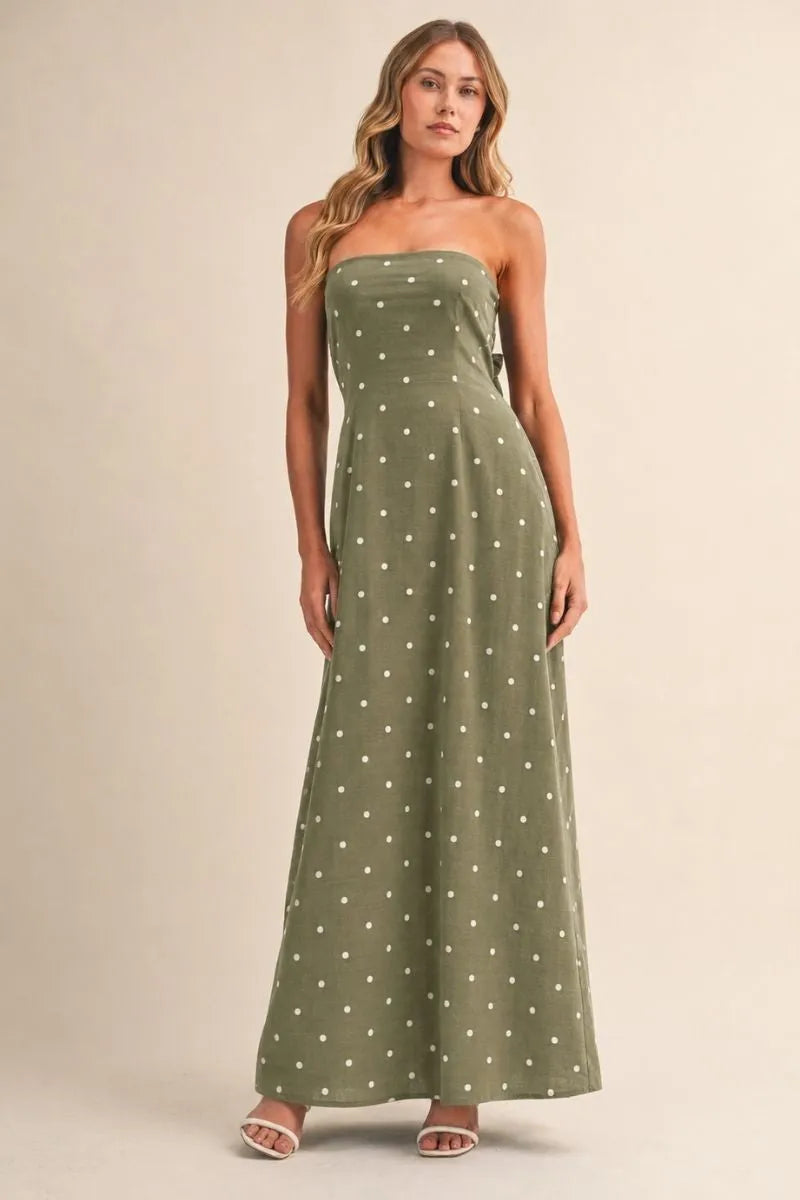 A flowing olive green polka dot tube maxi dress featuring a strapless tie back design and small white dots