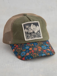 Olive green and tan mesh canvas trucker hat with a floral brim featuring blue orange and red blossoms mountains design