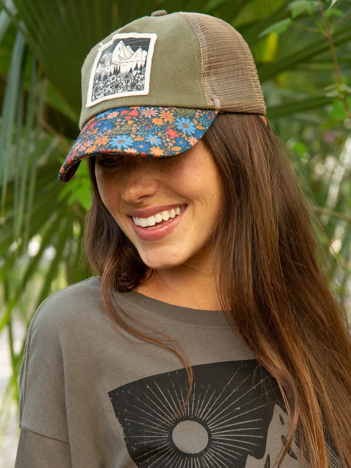 Olive green and tan canvas trucker hat with floral brim and white framed mountain patch design