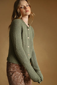 Olive green sweater knit cardigan with cream-colored buttons featuring textured knit fabric and button front closure
