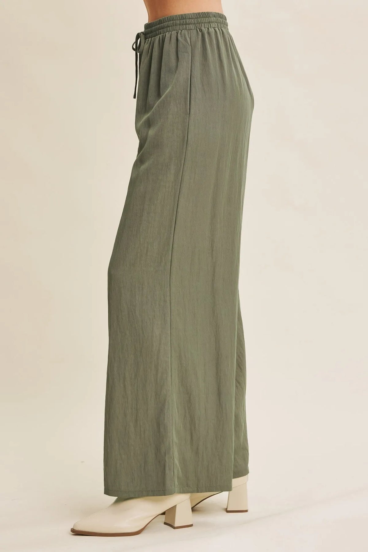 Olive green wide leg pants with elastic waistband and drawstring featuring a step washed look for casual wear