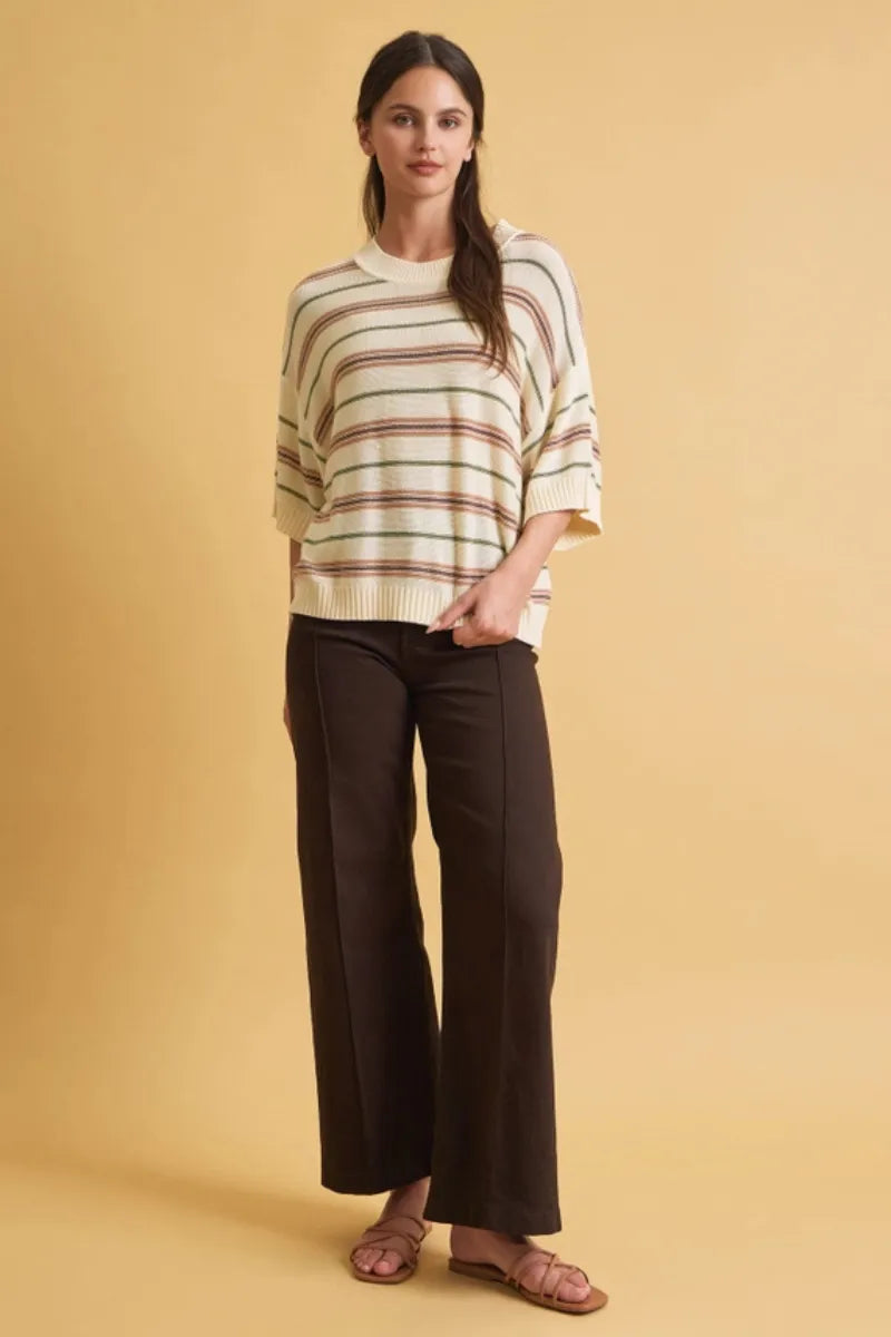 Cream-colored oversized cut half sleeve striped sweater with muted earth tone horizontal stripes and ribbed cuffs