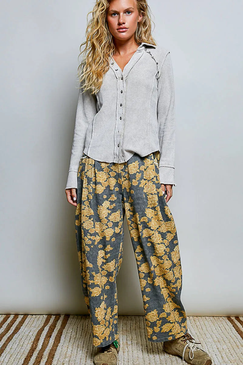 A pair of dark gray wide-leg trousers with bold golden-yellow floral pattern paired with a slim fit deep v collar shirt