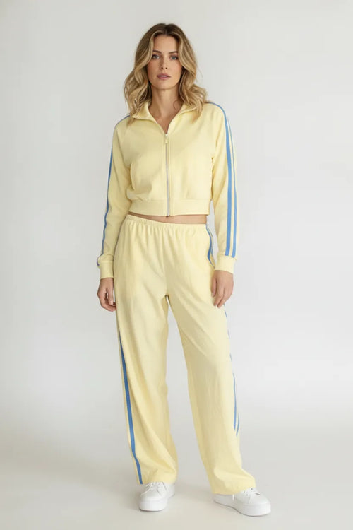 A pale yellow landon track cropped jacket with blue vertical stripes paired with matching track pocket side double line pants