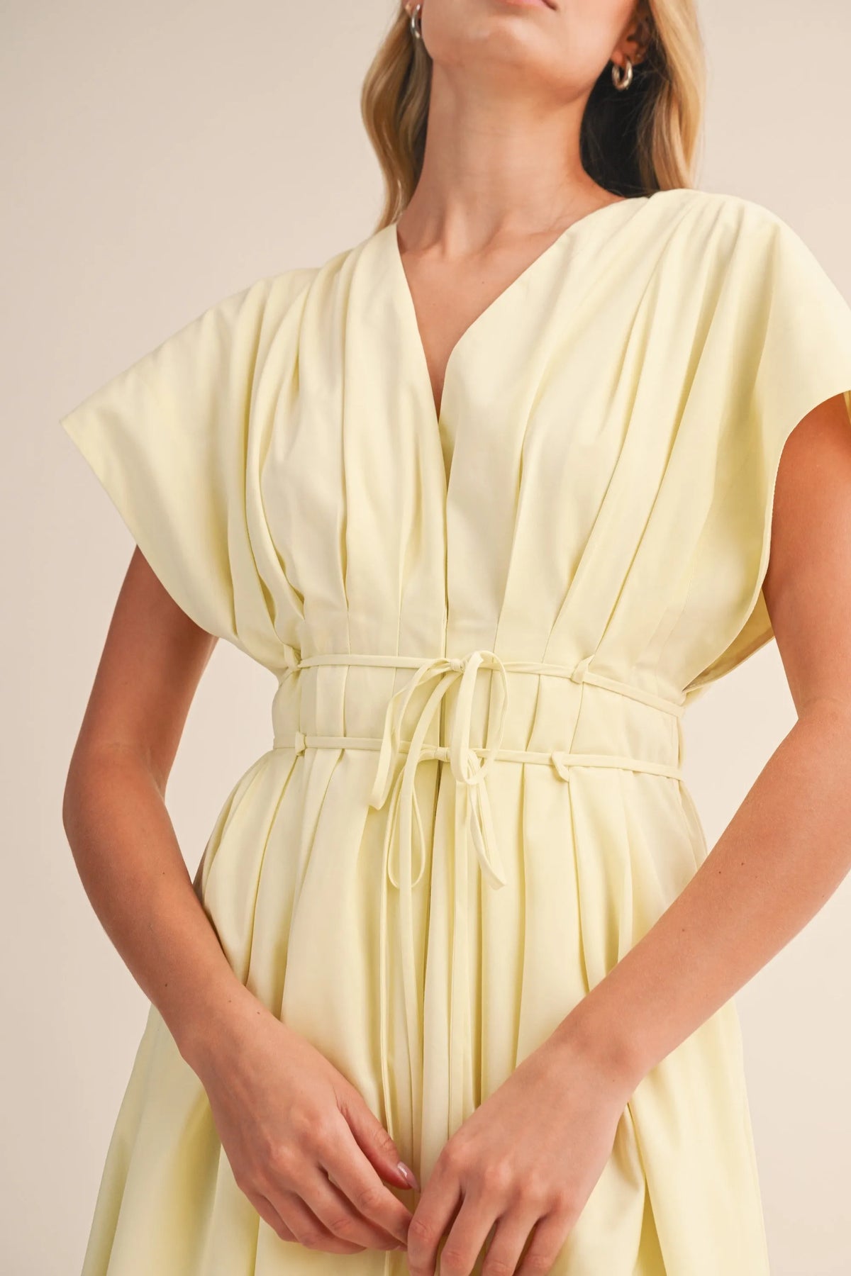 A pale yellow poplin short sleeve belted maxi dress with v-neckline and flutter sleeves featuring pleated detail