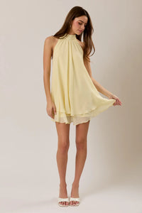 A flowing pale yellow halter neck ruffle mini dress with layered ruffle hem and lightweight fabric