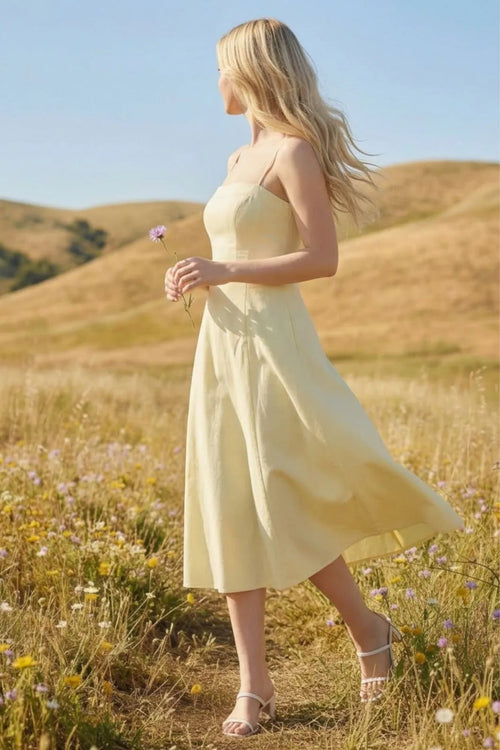 A flowing pale yellow sleeveless pleated a-line midi dress with fitted bodice and soft fabric