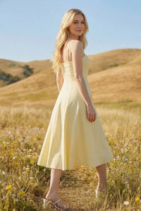 A pale yellow sleeveless pleated a-line midi dress with a fitted bodice and flared skirt for elegant wear