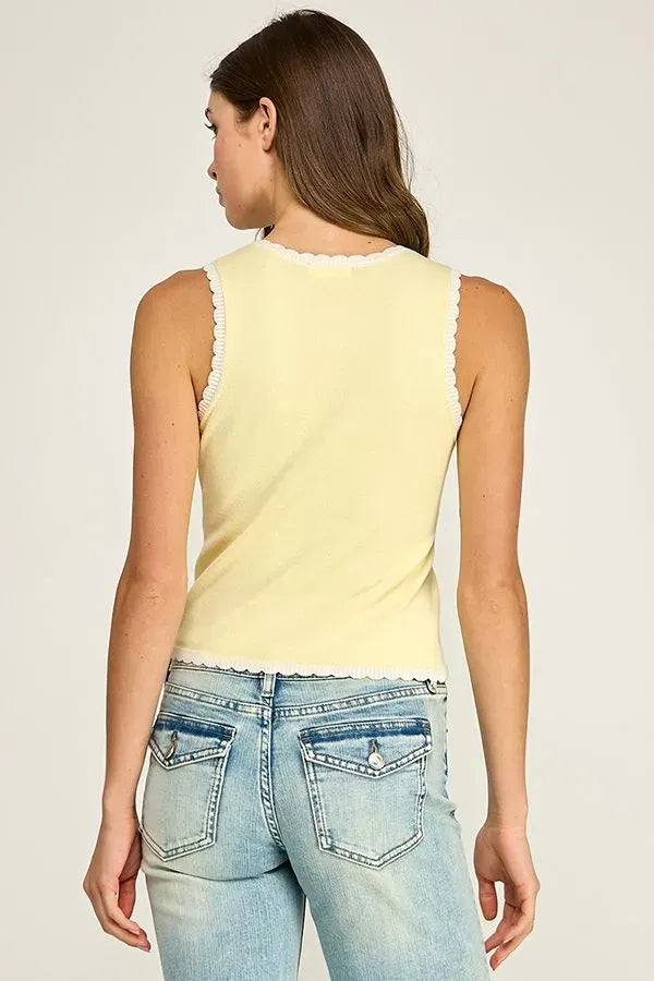 A pale yellow sleeveless scallop trim knit top with white lace trim along the neckline and hem