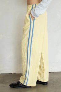 Pale yellow landon track pocket double line pants with wide legs and two vertical light blue stripes on each side