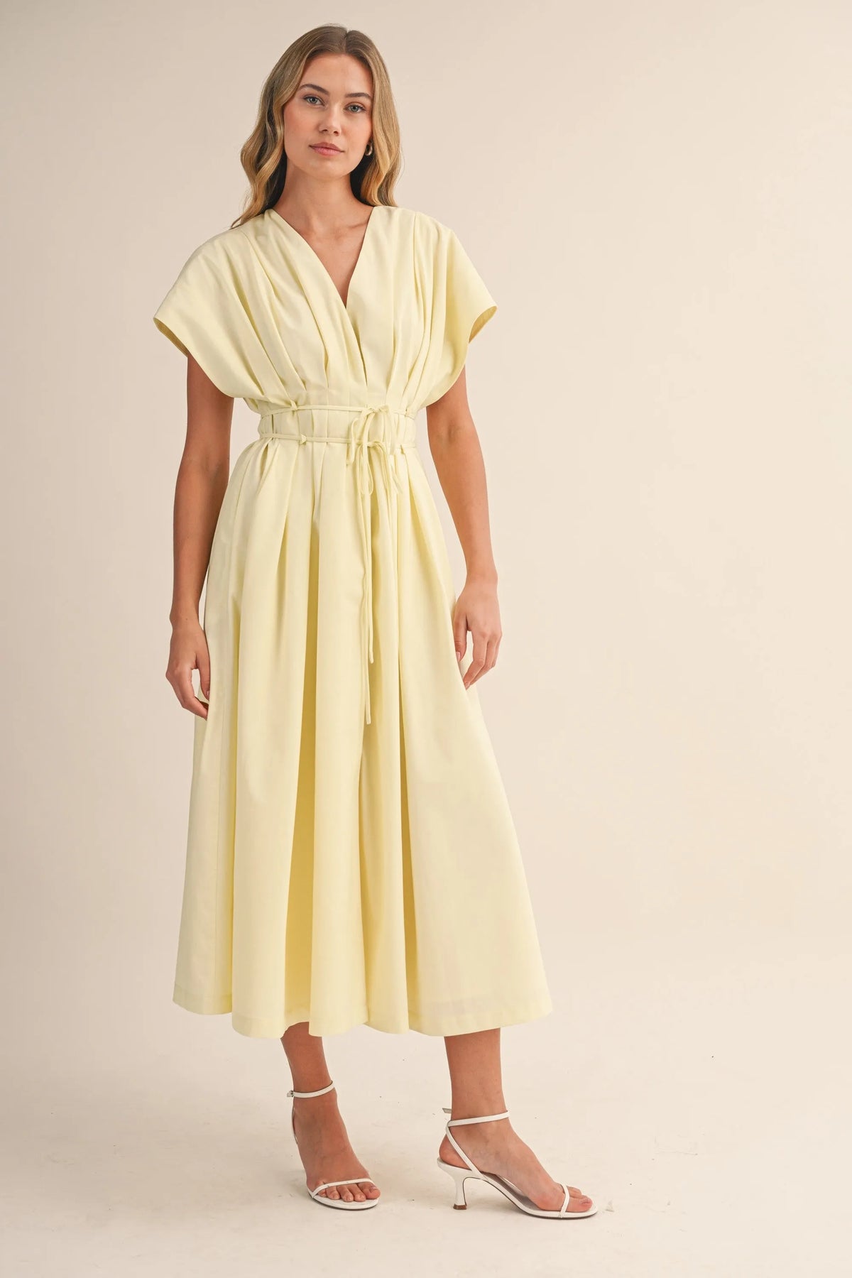 A flowing pale yellow poplin short sleeve belted maxi dress with pleated details and a matching waist belt