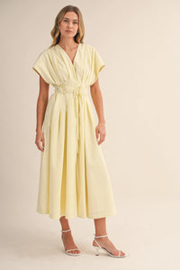 A flowing pale yellow poplin short sleeve belted maxi dress with pleated details and a matching waist belt