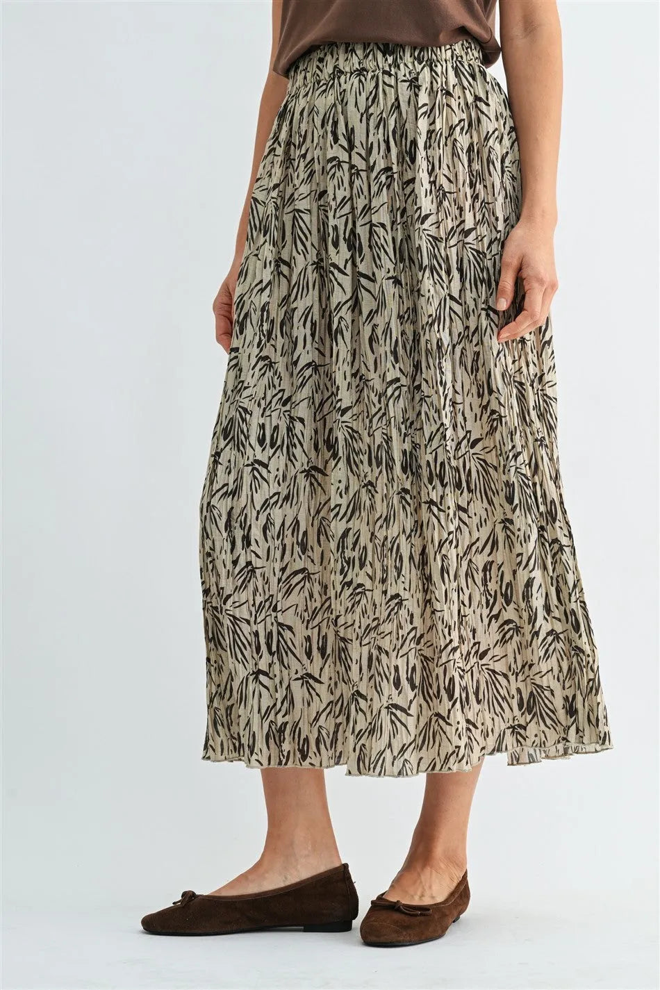 A flowing crinkle leaf print midi skirt in beige with black leafy patterns featuring pleated design