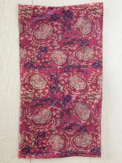 A worn magenta fabric boho bandeau headband with intricate muted purple and cream floral and vine patterns