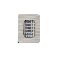 A rectangular white resin ribbed photo frame with brass inlay and an ornate brown damask patterned backing