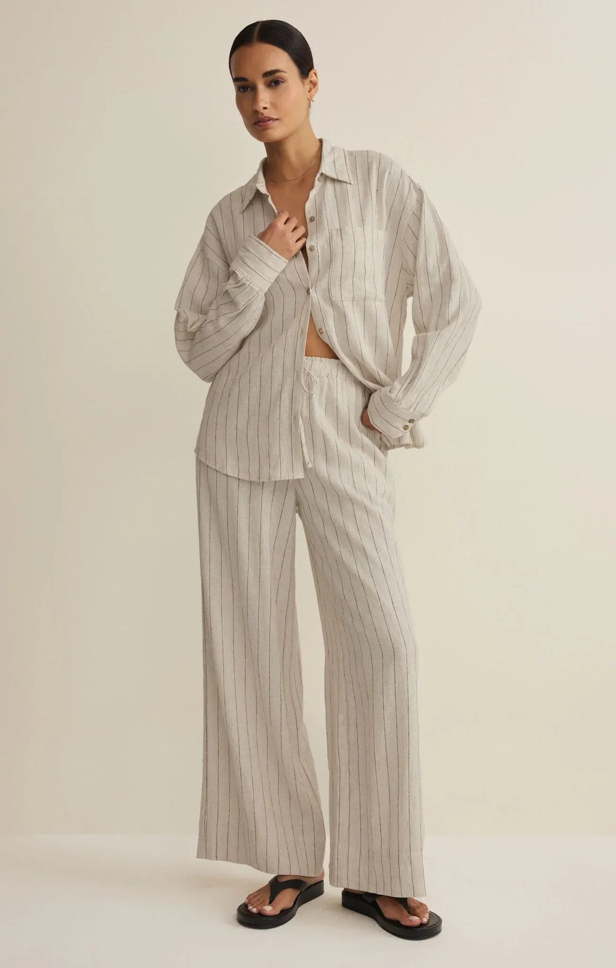 A relaxed oversized beige and white striped button-down shirt paired with henri striped wide leg pants