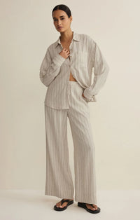 A relaxed oversized beige and white striped button-down shirt paired with henri striped wide leg pants