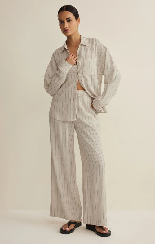 A relaxed oversized beige and white striped button-down shirt paired with henri striped wide leg pants