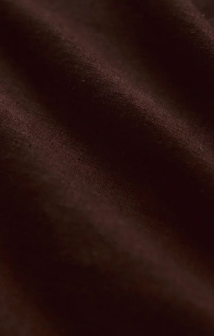 Rich burgundy silk fabric with smooth lustrous texture and subtle sheen featured in alfie linen button up shirt