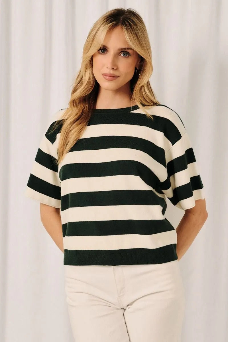 A woman wears a black and cream crew neck cropped striped sweater top with a relaxed fit and round crew neck design