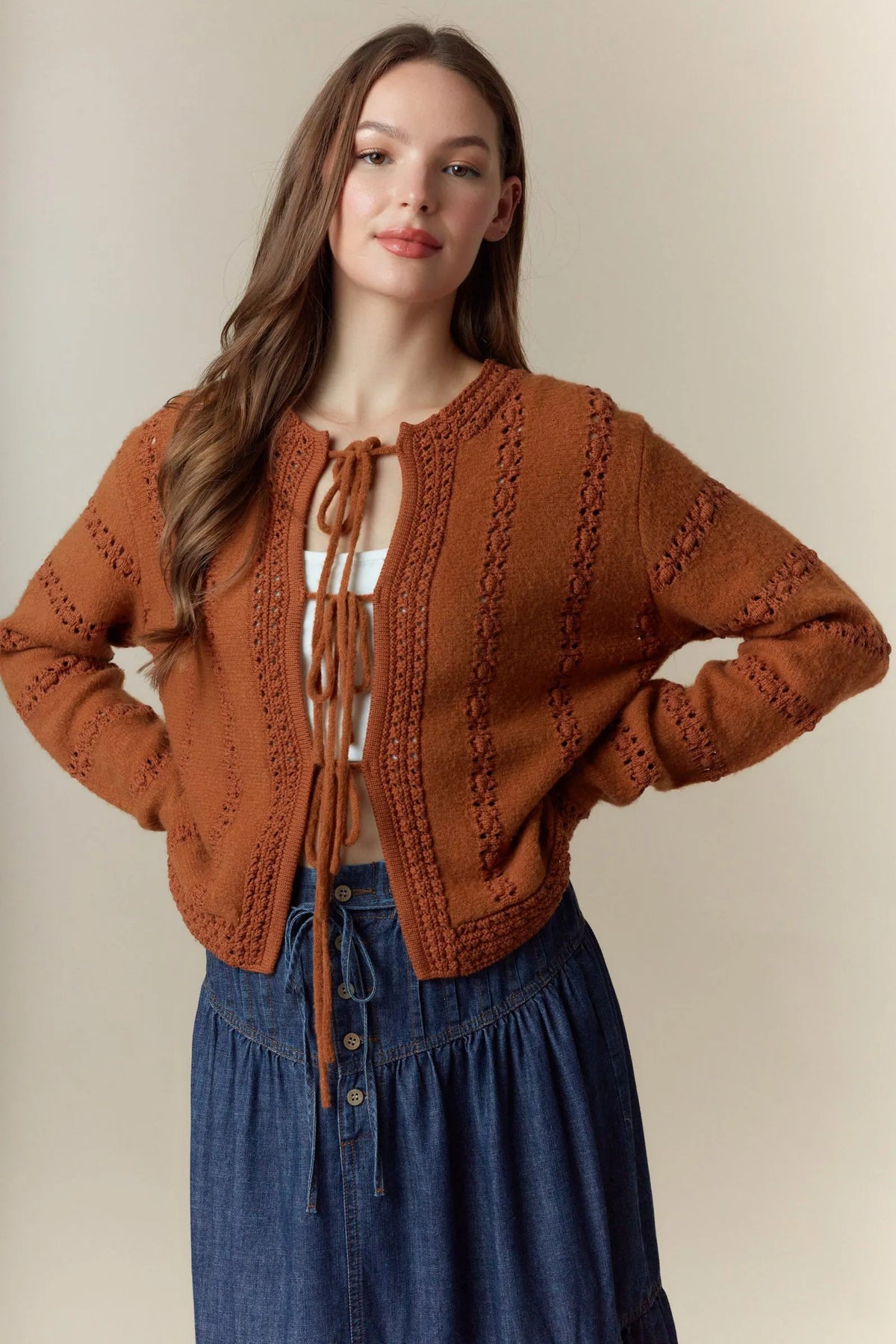 Rust-colored knitted cropped cardigan with hole stripe bows front tie and intricate cable-knit patterns