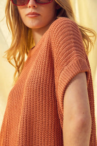 A rust-colored dolman sleeve knitted top with short sleeves and a relaxed fit in textured knit fabric