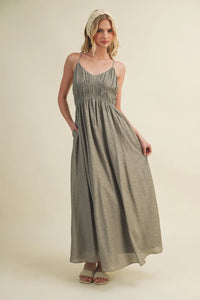 A flowing sage green linen maxi dress with a shirred bodice and thin bodice spaghetti straps