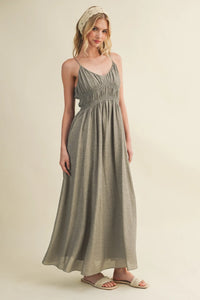 A flowing sage green maxi dress featuring a shirred bodice and delicate bodice spaghetti straps