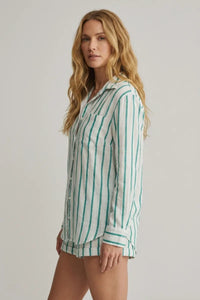 A woman wearing a white and green vertically striped long-sleeved saturdays stripe button down shirt with rolled cuffs