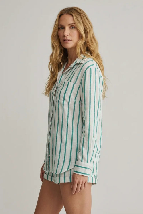 A woman wearing a white and green vertically striped long-sleeved saturdays stripe button down shirt with rolled cuffs